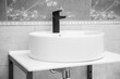 Black faucet for water and white separate high sink on stone pedestal. Loft style bathroom