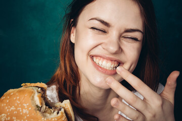 Wall Mural - woman eating hamburger fast food snack close-up