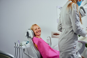 Wall Mural - Smiling patient showing bright smiley while sitting on dental chair