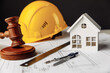 Judge gavel, white house and yellow hard hat with drawing tools on construction plan. Law concept