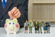 Saving for retirement and pension fund concept : Senior retired couple stand near a piggybank, a man insert money in a deposit box for future expenses, depicting long-term investment for aging society