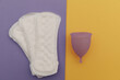 Purple menstrual cup and pads on a colorful background. Ways of women's hygiene