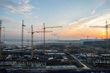 Construction cranes on the background of the sunset.