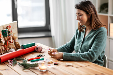 winter holidays, diy and hobby concept - woman making advent calendar or packing christmas gift at home