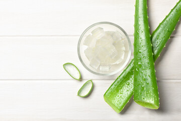 Wall Mural - Top view of Fresh Aloe vera leaves with gel in glass bowl on white wood.