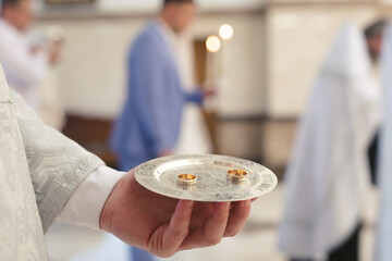 Close-up photo of a wedding ring held by a priest in a church before the wedding ceremony