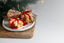 Different Festive Shape Shortbread Cookies Stacks With Red Ribbon And Bow On White Plate With Christmas Tree Branch