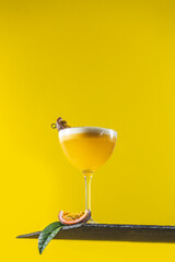 Wall Mural - Glass of fresh passion fruit Martini cocktail on bright yellow background