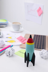 Poster - Toy rocket, laptop and crumpled paper on messy table indoors. Startup concept