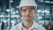 Portrait of a Young Handsome Confident Engineer Wearing Safety Goggles and White Hard Hat in Office at Car Assembly Plant. Industrial Specialist Working on Vehicle Production in Modern Factory.