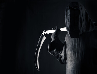 Death holding an old scythe sharp blade on shoulders of death in darkness fear