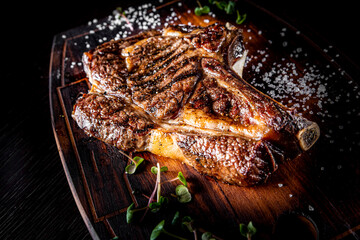 Sticker - Grilled Ribeye Steak on bones on wooden board, prime cowboy steak on dark background