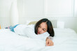 © Ekkasit A Siam - Portrait Cute Asian teen with long hair Wearing a white shirt and lazing around in bed happily in the bedroom.