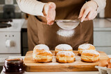 Fototapeta  - Woman prepares fresh donuts with jam in home kitchen. Cooking traditional Jewish Hanukkah sufganiyot.