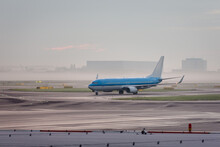 Airplane Taxing On Runway At Amsterdam Schiphol International Airport During Early Morning Mist