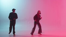 Professional Choreographers Dancing Hip Hop On Color Changing Neon Background. Man And Woman Dancers Showing Movements, Pair Dance, Duet. Modern Dance School For Teenagers.