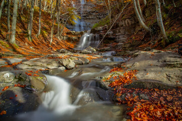 Stream with waterfall in the woods of the Reggio Apennines. On an autumn day in the foliage of the trees. Lavacchiello waterfalls