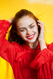 Fototapeta Tęcza - smiling woman in red dress posing yellow background