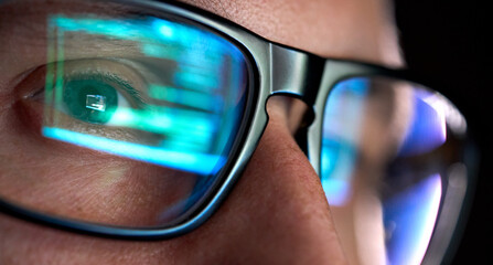 focused developer coder wears glasses working on computer looking at programming code data cyber sec
