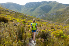 A Teenage Girl Walking Along A Path In The Mountains With A Backpack