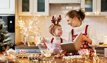 Wall Mural - Young smiling woman mother making dough for christmas gingerbread cookies with cute little son