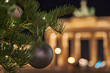Germany Berlin, Christmas tree in front of illuminated Brandenburg Gate in Berlin City in the evening with dark sky, blurred  background with a beautiful bokeh, chrismas ball in front of the gate   
