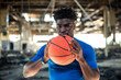 © Cavan Images - Black boy holding a basketball in an abandoned warehouse.