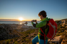 Young Man Take Pictures At Sunrise Over Rocky Landscape, Costa Blanca