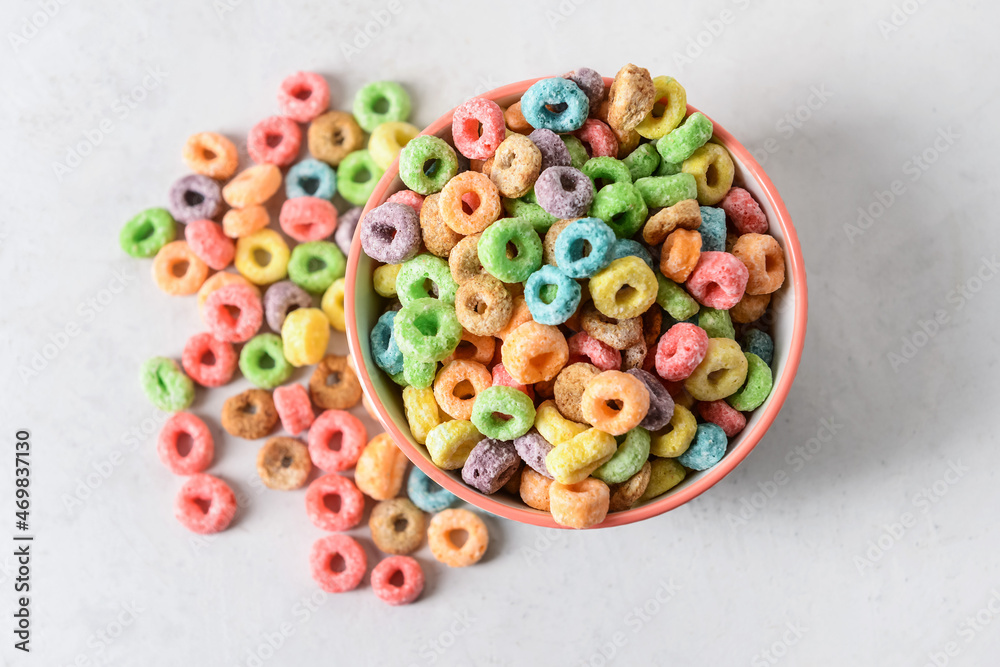 Bowl with crunchy corn flakes rings on light background