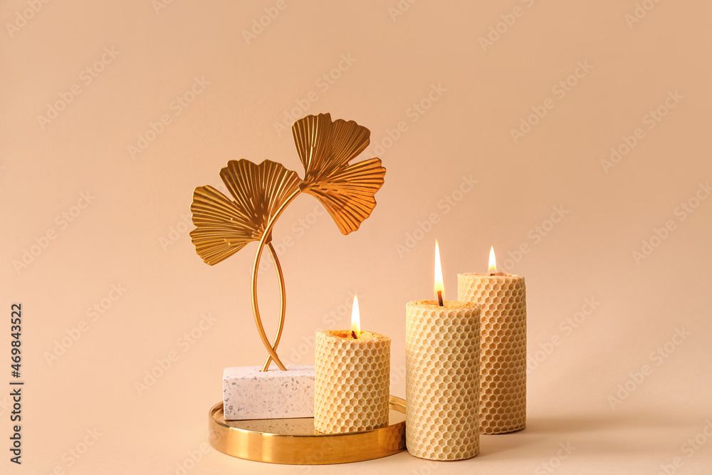 Burning candles and tray with decor on beige background