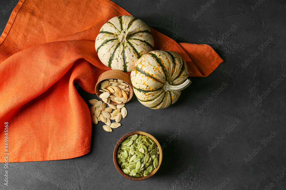 Bowls with pumpkin seeds on black background