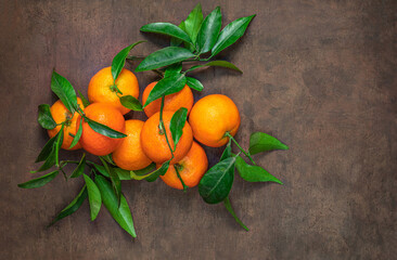 Wall Mural - Sweet Mandarines oranges fruits or tangerines with green leaves on a wooden table. Copyspace. Fresh picked mandarins Top view.