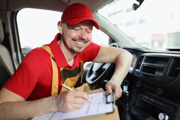 Smiling delivery service worker fill in necessary documents after shipping