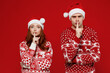 Young couple friends two man woman in sweater hat secret woman say hush be quiet finger on lips shhh gesture isolated on plain red background studio portrait. Happy New Year 2022 celebration concept.