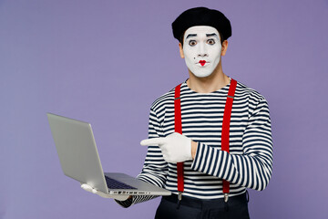 Wall Mural - Charismatic puzzled fun young mime man with white face mask wears striped shirt beret hold use work point finger on laptop pc computer isolated on plain pastel light violet background studio portrait.