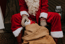 Person Wearing Santa Costume Holding Christmas Present