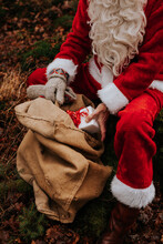 Person Wearing Santa Costume Holding Christmas Present
