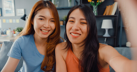 Sticker - Teenager Asian women feeling happy smiling selfie and looking to camera while relax in living room at home. Cheerful Roommate ladies video call with friend and family, Lifestyle woman at home concept.