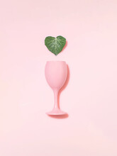 Pink Glass And Ivy Heart Shaped Green Leaf Against Pastel, Milky Background.  Minimal Creative Layout, Skin Care, Hydration, Natural Beauty, Love.