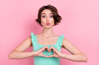 Portrait of attractive amorous girl showing heart symbol sending air kiss affection isolated over pink pastel color background