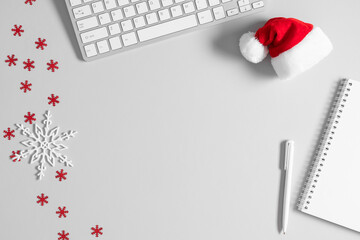 Christmas or New Year background. Office table, santa hat, christmas decorations, keyboard on gray table. Flat lay, top view, copy space