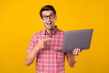 Canvas Print - Portrait of attractive trendy cheerful guy geek using demonstrating laptop sign isolated over bright yellow color background