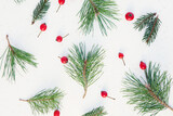 Fototapeta Do pokoju - Christmas composition. Pine green branches with red berries on white background. Christmas background, top view, horizontal image.
