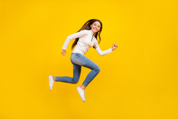Wall Mural - Full size profile photo of nice brunette teenager girl run wear pullover jeans shoes isolated on yellow color background