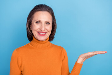 Poster - Photo of positive satisfied person toothy smile arm palm hold empty space promo isolated on blue color background