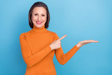 Poster - Portrait of glad friendly attractive lady direct finger hand palm empty space isolated on blue color background