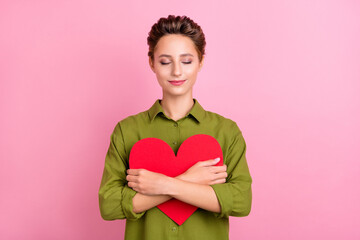 Poster - Photo of charming sweet young lady wear green blouse embracing big red heart smiling isolated pink color background