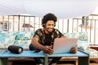 © ADDICTIVE STOCK - Cheerful black man in headphones browsing laptop