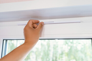 Supply ventilation on a plastic window, a man's hand moves the ventilation lever on the window