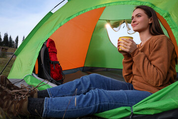 Wall Mural - Young woman with cup of drink in camping tent outdoors